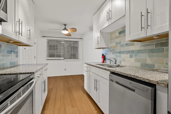 a kitchen with granite countertop a sink stove and cabinets