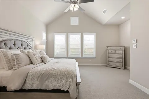 a spacious bedroom with a bed a dresser and a chandelier