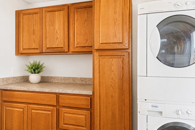 69 South Main Street Manti, UT 84642 - Photo 25 of 44 Laundry area featuring wood-finish cabinetry, a stacked washer and dryer, and a patterned countertop