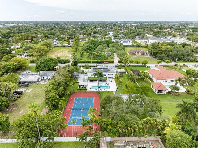 an aerial view of residential houses with outdoor space and trees