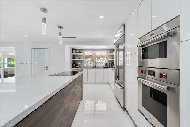 a kitchen with stainless steel appliances kitchen island granite countertop a refrigerator oven a sink dishwasher and white cabinets with wooden floor