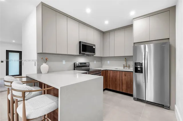 a kitchen with stainless steel appliances granite countertop a refrigerator a stove a sink a dining table and chairs