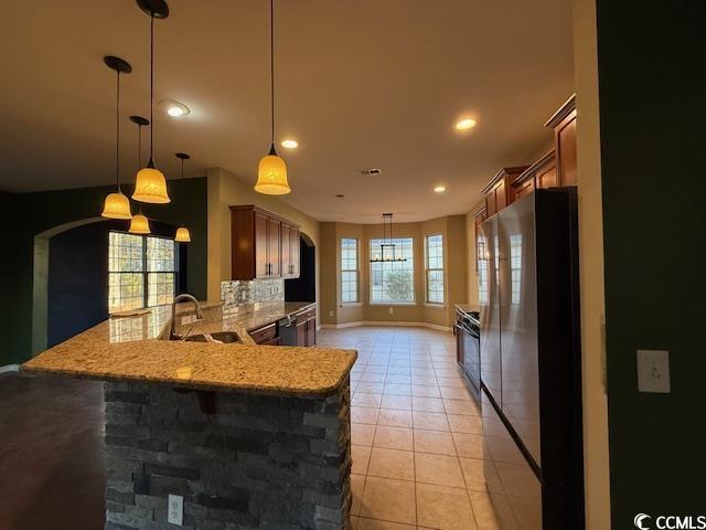237 Golden Oaks Drive Murrells Inlet, SC 29576 - Photo 16 of 21 Kitchen featuring pendant lighting, freestanding refrigerator, light stone countertops, a kitchen breakfast bar, and light tile patterned flooring