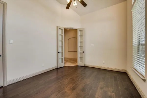 an empty room with wooden floor cabinet and windows