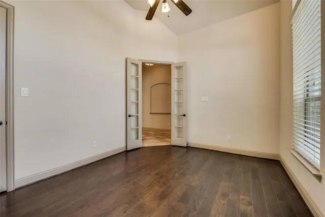 an empty room with wooden floor cabinet and windows