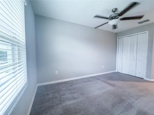 en empty room with windows and ceiling fan