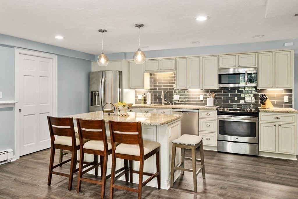 1 Barnbridge Circle Framingham, MA 01701 - Photo 29 of 42 a kitchen with stainless steel appliances kitchen island granite countertop a table chairs microwave and sink