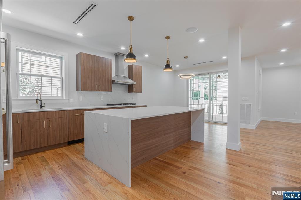 24 Ryder Road Fair Lawn, NJ 07410 - Photo 17 of 19 a large kitchen with stainless steel appliances kitchen island a large counter space a sink wooden floor and a window