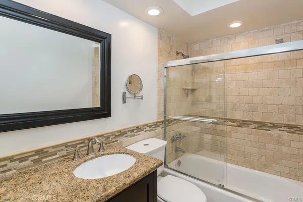 a bathroom with a granite countertop sink mirror toilet and bathtub