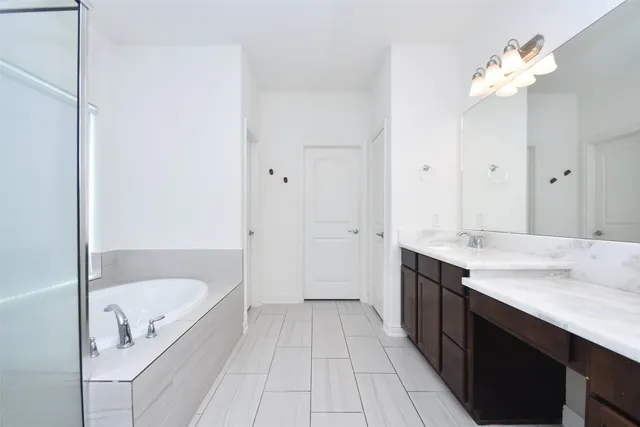 a bathroom with a tub a sink and a mirror