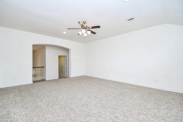 an empty room with windows and chandelier fan