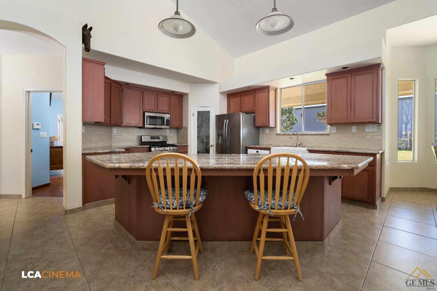 Undisclosed Address Bakersfield, CA 93314 - Photo 7 of 33 a kitchen with stainless steel appliances granite countertop a stove a sink a microwave a refrigerator with a dining table and chairs