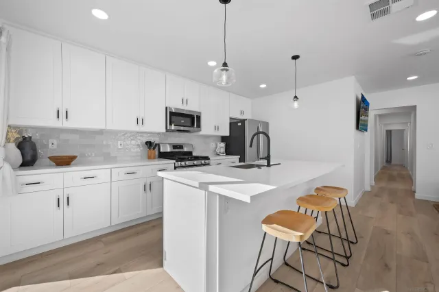 a kitchen with stainless steel appliances granite countertop a sink a stove a refrigerator and cabinets with wooden floor