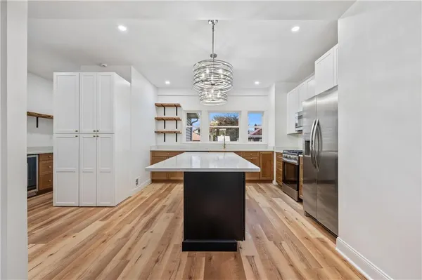 a kitchen with stainless steel appliances a dining table chairs stove and refrigerator