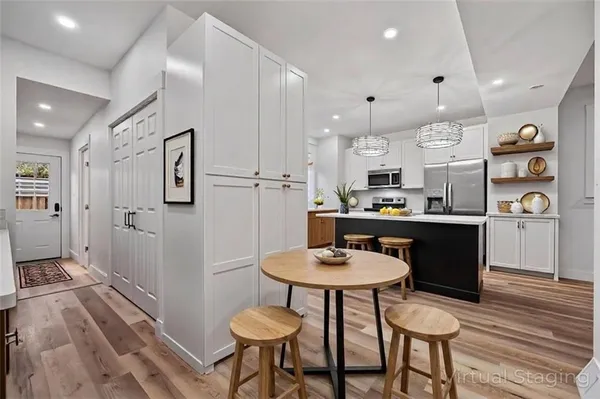 a kitchen with stainless steel appliances kitchen island granite countertop a table chairs and a refrigerator