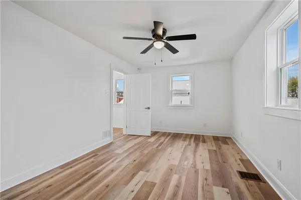 a view of empty room with wooden floor and fan