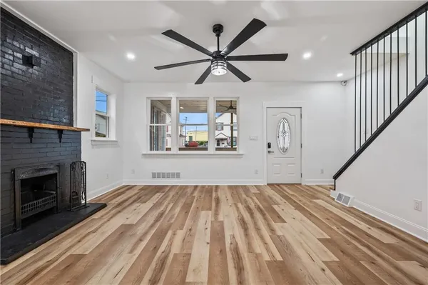 a view of a livingroom with wooden floor a ceiling fan and a fireplace