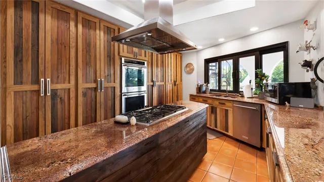 a kitchen with stainless steel appliances kitchen island granite countertop a refrigerator and a stove