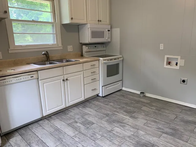 a kitchen with granite countertop white cabinets and white appliances