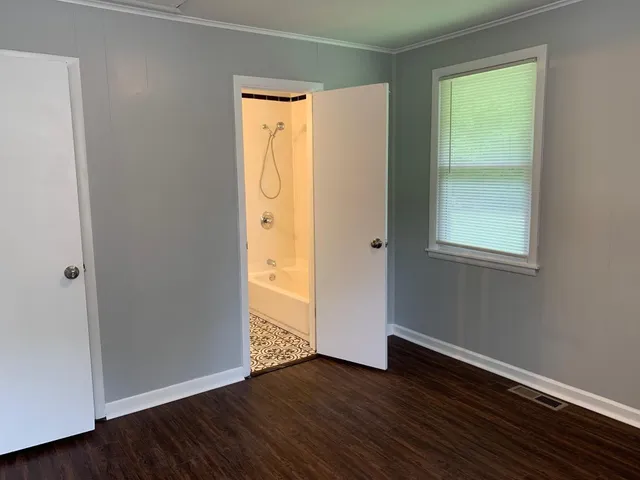 a view of an empty room with wooden floor and a window