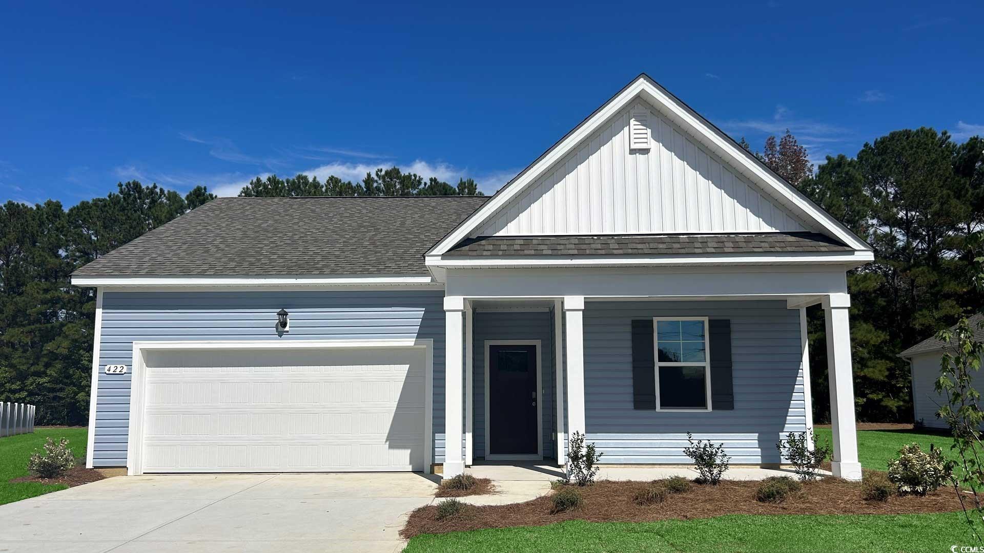 View of front facade with board and batten siding, covered porch, an attached garage, a shingled roof, and driveway