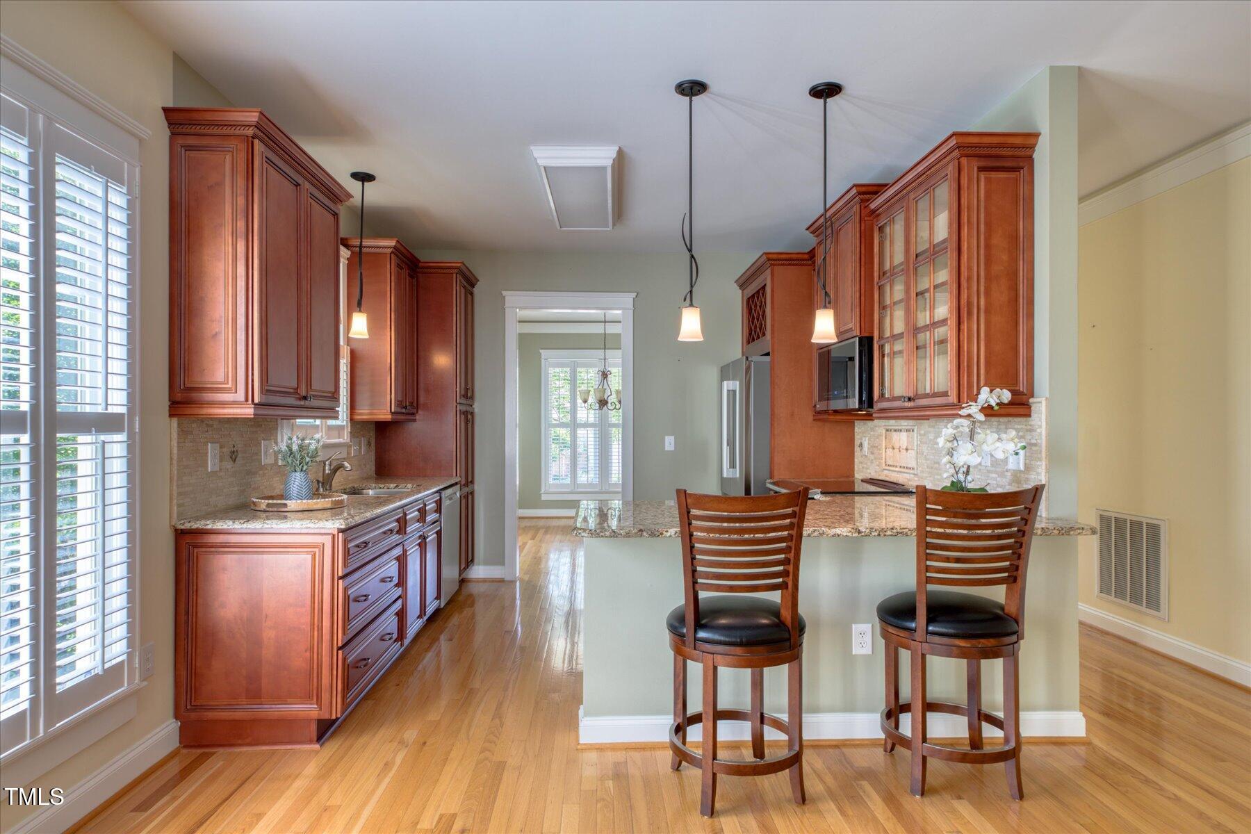 121 Bridgegate Drive Cary, NC 27519 - Photo 10 of 38 a kitchen with stainless steel appliances kitchen island granite countertop a table chairs and a wooden floors