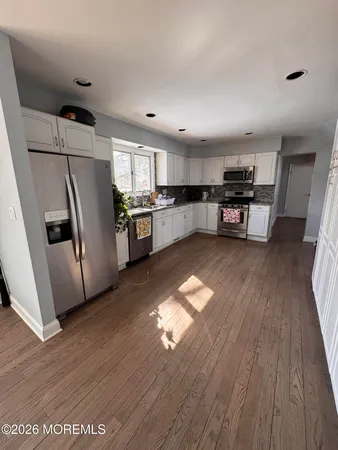 a kitchen with refrigerator and wooden floor