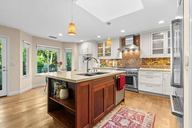 a kitchen with stainless steel appliances kitchen island granite countertop a table chairs and a refrigerator