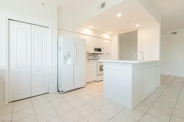 a kitchen with stainless steel appliances a refrigerator sink and white cabinets