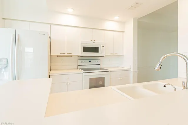 a kitchen with stainless steel appliances a sink a stove a refrigerator cabinets and a window