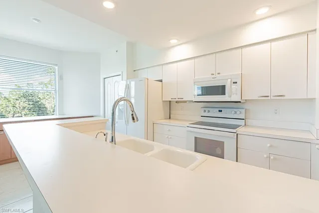 a kitchen with a sink a stove a refrigerator and white cabinets