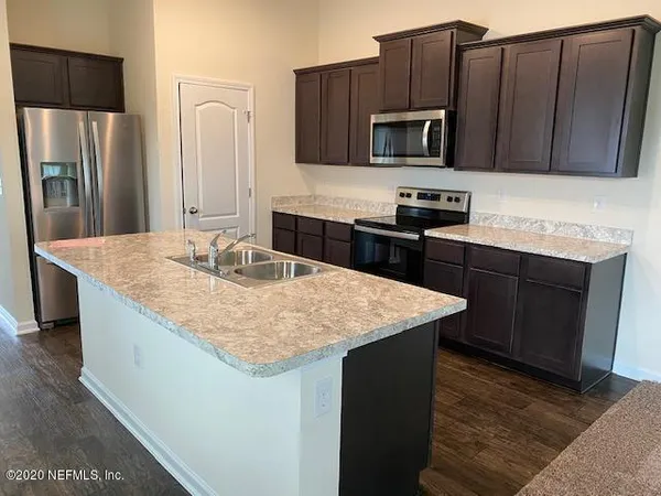 a kitchen with granite countertop wood cabinets stainless steel appliances and a sink