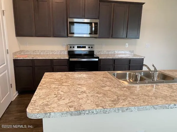 a kitchen with kitchen island granite countertop a sink stove and microwave