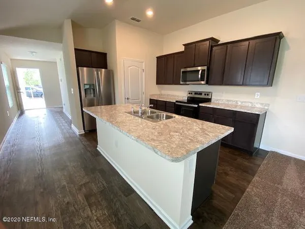 a kitchen with granite countertop kitchen island wooden cabinets a refrigerator and a stove
