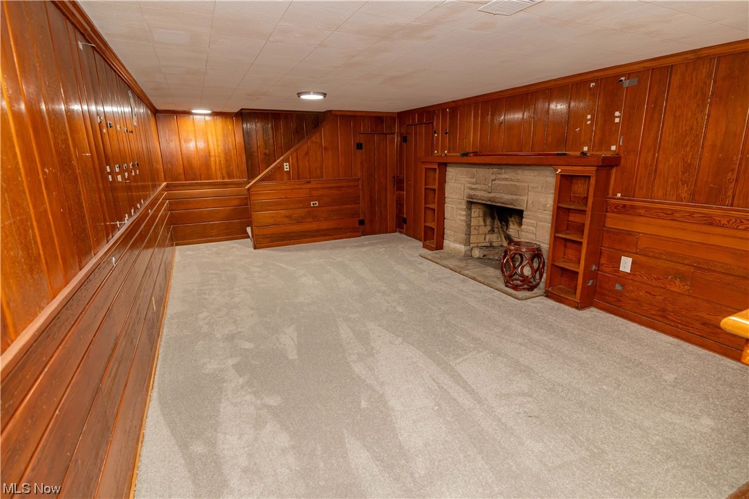 4591 Birchwold Road South Euclid, OH 44121 - Photo 26 of 35 Unfurnished living room featuring light carpet, a fireplace, and wooden walls