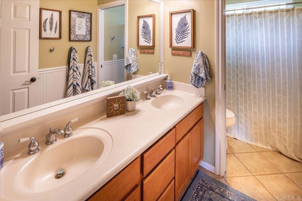25057 Poderio Drive Ramona, CA 92065 - Photo 22 of 36 a bathroom with a double vanity sink and a mirror