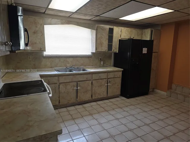 a kitchen with a sink a window and refrigerator