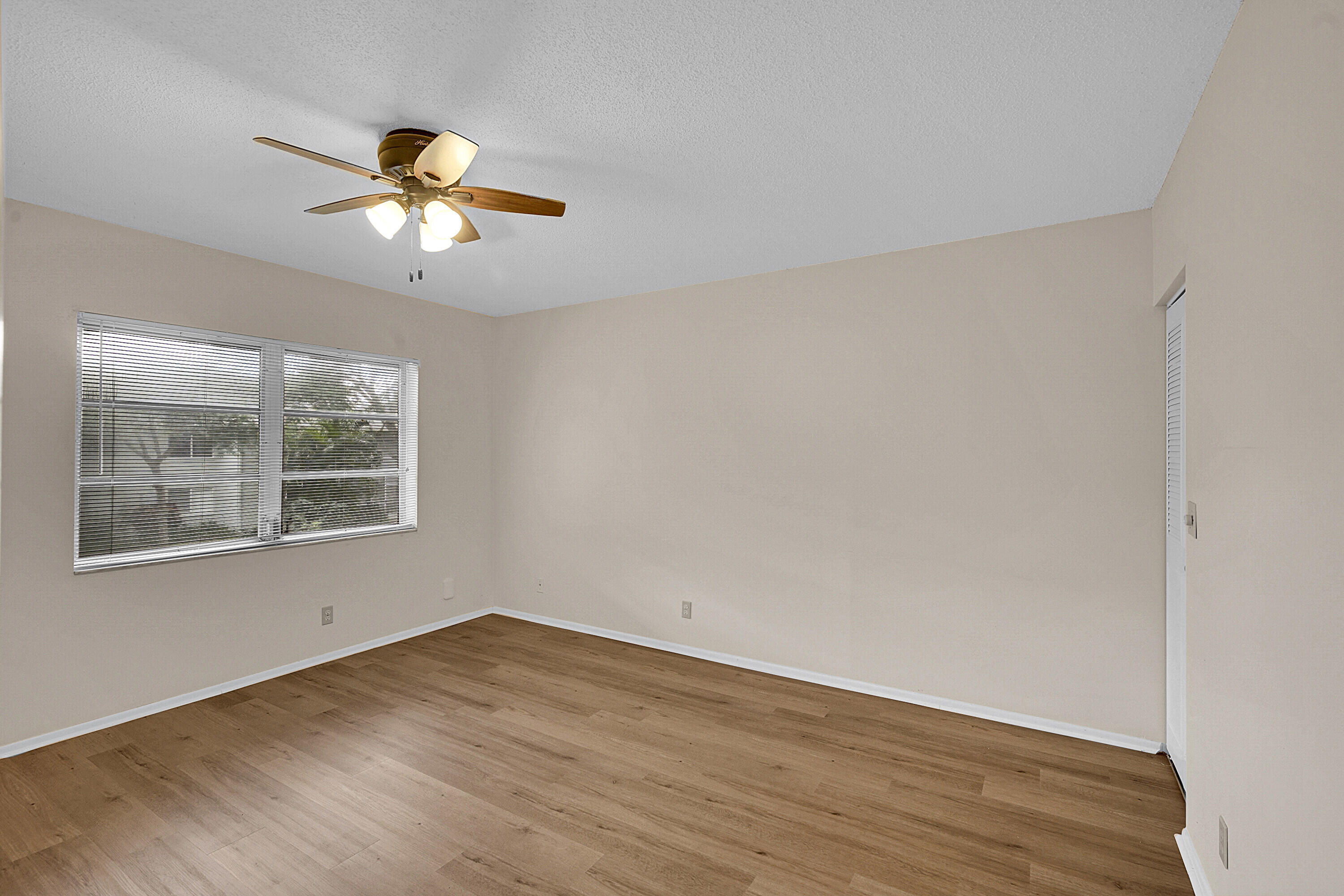 2340 Southwest 22nd Avenue, Unit 306 Delray Beach, FL 33445 - Photo 19 of 33 a view of an empty room with wooden floor and a window