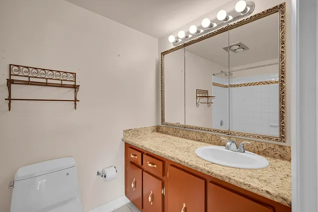 a bathroom with a granite countertop sink a toilet and shower