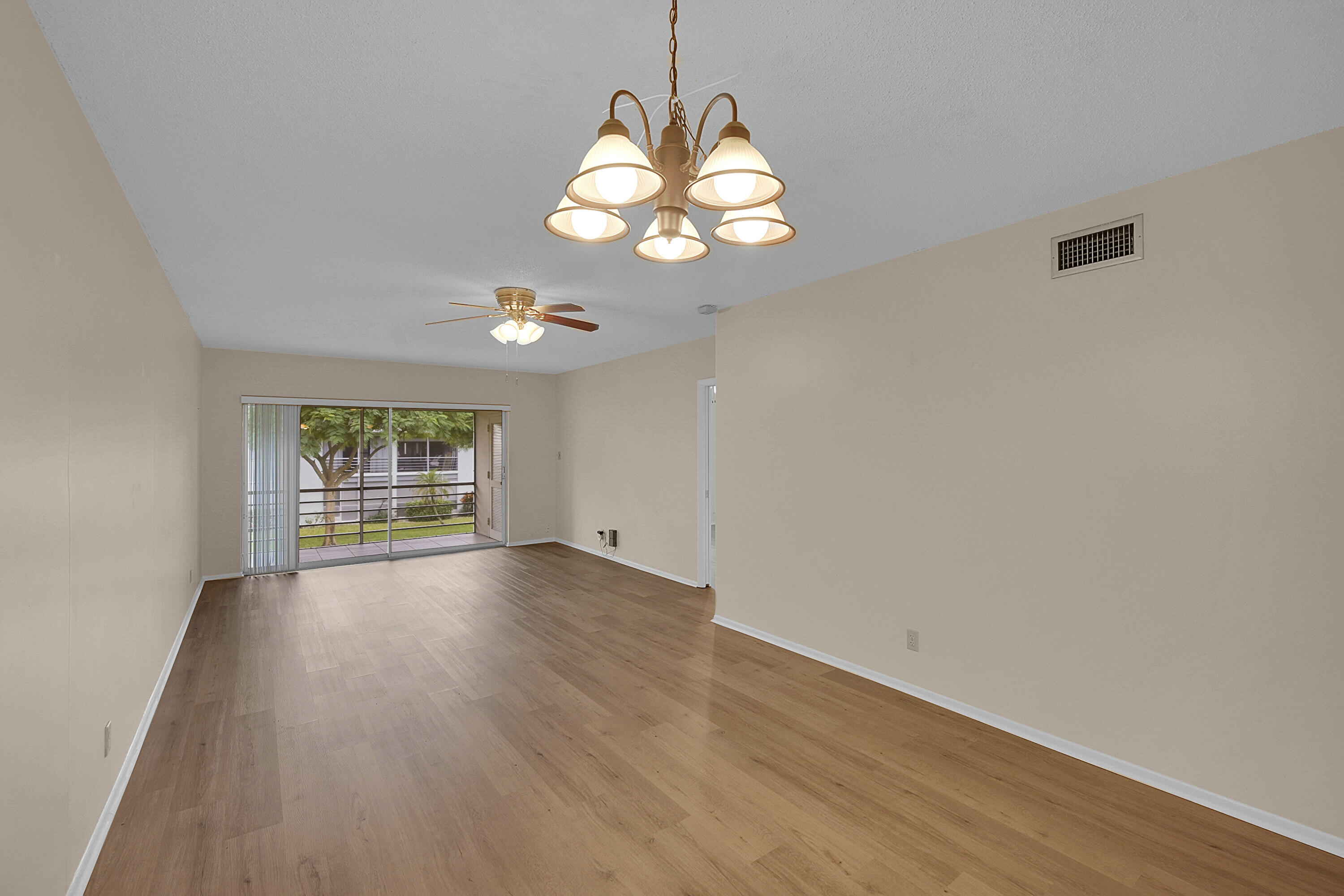 2340 Southwest 22nd Avenue, Unit 306 Delray Beach, FL 33445 - Photo 8 of 33 an empty room with wooden floor chandelier and windows