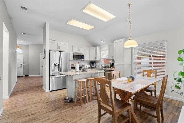 a kitchen with a dining table chairs stainless steel appliances and cabinets