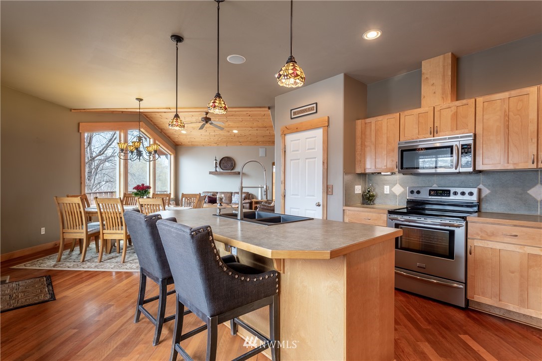 2805 Squilchuck Road Wenatchee, WA 98801 - Photo 11 of 34 a kitchen with stainless steel appliances granite countertop a stove a sink a microwave a dining table and chairs with wooden floor