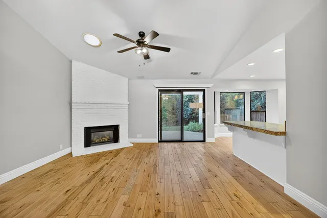 a view of kitchen and empty room with wooden floor