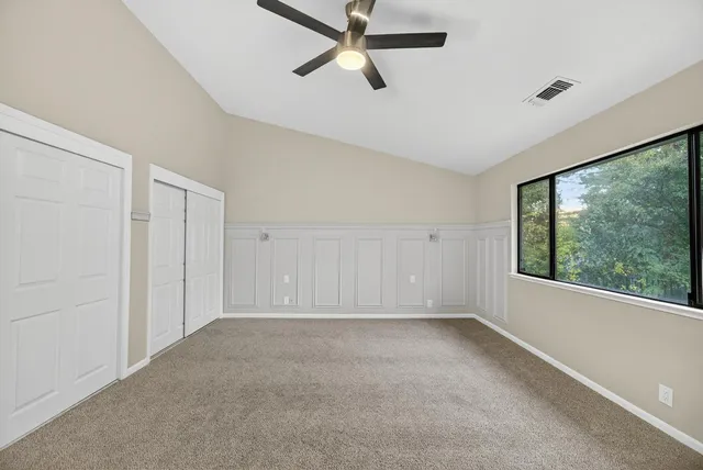 a view of an empty room and chandelier fan