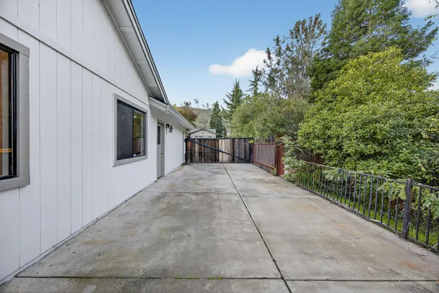 a backyard of a house with lots of plants and large trees
