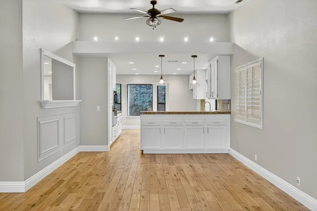 a large white kitchen with kitchen island a stove a sink dishwasher and wooden floor
