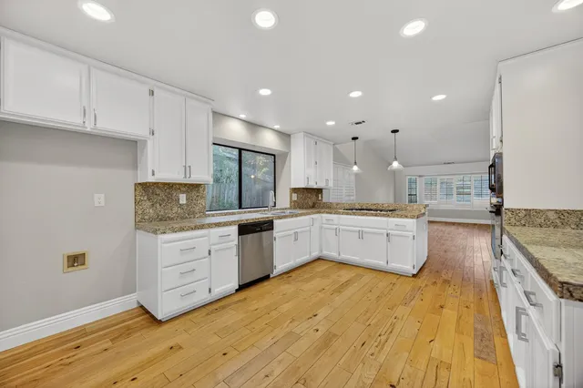 a large kitchen with stainless steel appliances granite countertop a stove and a large window