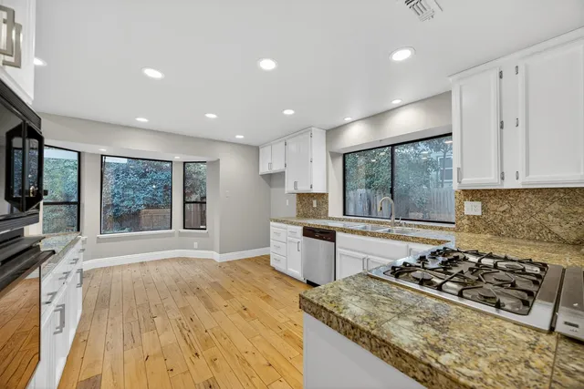 a large white kitchen with a large window a sink and stainless steel appliances