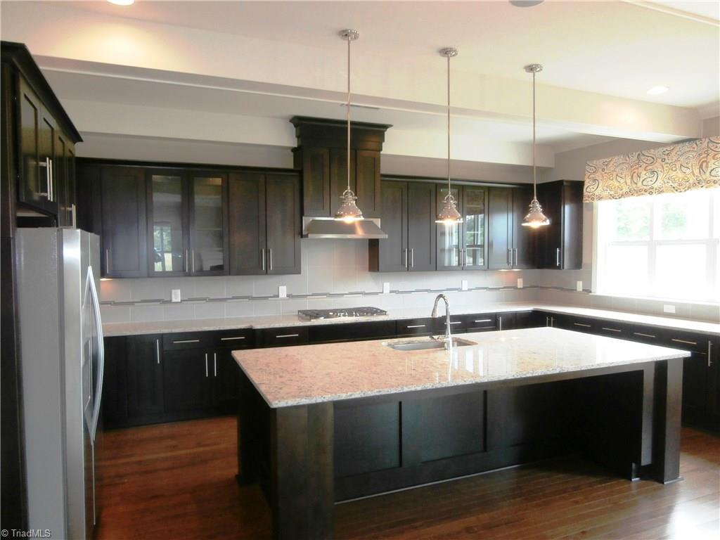 7797 Panda Court Oak Ridge, NC 27310 - Photo 7 of 23 Additional view of the kitchen. Notice the cabinets continue around the right side of the kitchen and the huge window gives you that light and airy atmosphere.