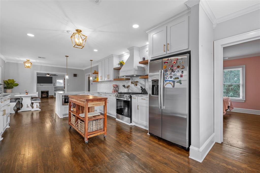 628 North 33rd Street Waco, TX 76710 - Photo 12 of 35 a kitchen with stainless steel appliances granite countertop a refrigerator a stove top oven a sink dishwasher and white cabinets with wooden floor